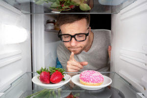 Mann muss sich zwischen Obst und Donut entscheiden