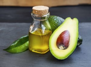 Als Naturkosmetik liegt eine Avocado mit Öl auf einem Tisch