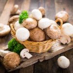 Egerlinge und weiße Champignons im Korb