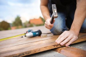 Mann bearbeitet Holzterrasse am haus