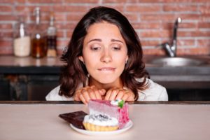 Frau sitzt vor Süßigkeiten.