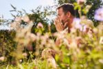 mann mit heuschnupfen niest in einem blumenfeld