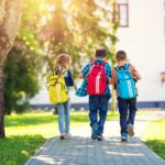Kinder mit Rucksäcken vor der Schule