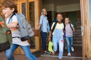 Kinder rennen lachend aus einer Schule