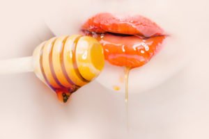 Als Küchenkosmetik schmiert sich eine Frau Honig auf die Lippen.