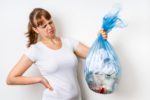 Frau hält angewidert Mülltüte