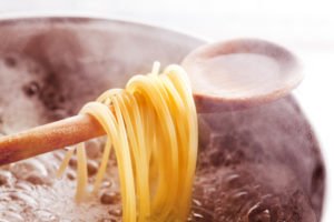 Spaghetti hängen über dem Kochlöffel im Kochenden Wasser