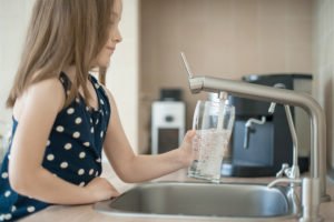 kind fuellt glas aus wasserhahn