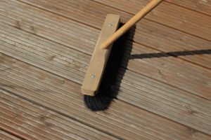 Holzterrasse mit dem Besen reinigen