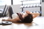 Trainieren mit Muskelkater: Frau liegt müde vom Training am Boden.