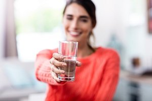 Frau hält ein Glas mit Wasser.