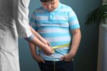Kind mit Übergewicht wird gerade am Bauch gemessen
