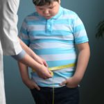 Kind mit Übergewicht wird gerade am Bauch gemessen